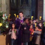 Les enfants autour du père Pierre à côté de la crèche